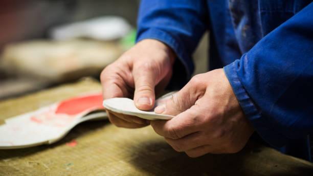 A man is engaged in shoe repair, utilizing a tool to enhance the quality and durability of the footwear