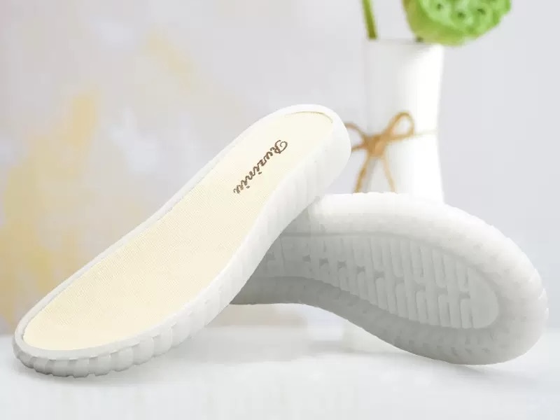 Close-up of a pair of white rubber shoe soles with a textured pattern, demonstrating material options for adhesive selection.