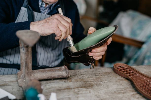 Old worker making shoes for men