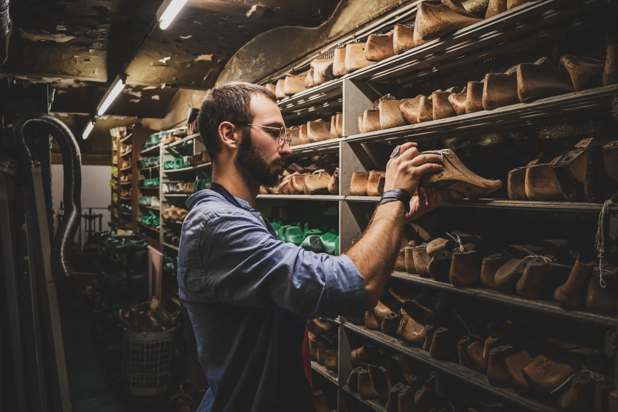 focused bearded cobbler is looking right shoe form storage