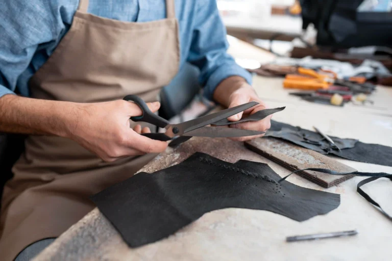 A tailor is cutting the upper part of a shoe.