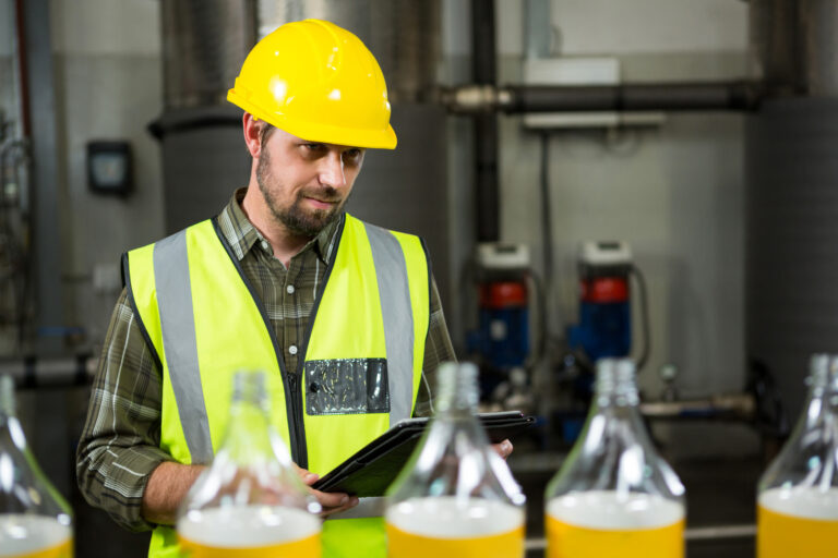 Thoughtful male worker with digital tablet in juice factory