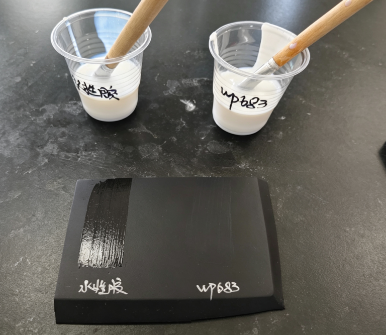 Water-based adhesive test on a dark board: standard PU glue leaves a shiny mark beside HELEY WP683.